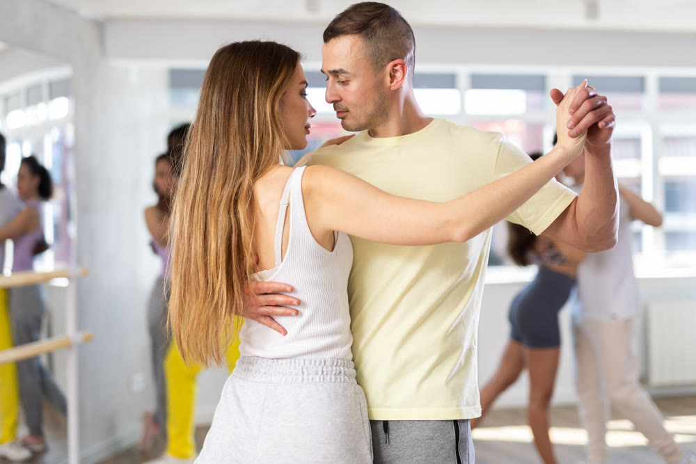 Young man and woman practicing salsa dance in pair in training hall