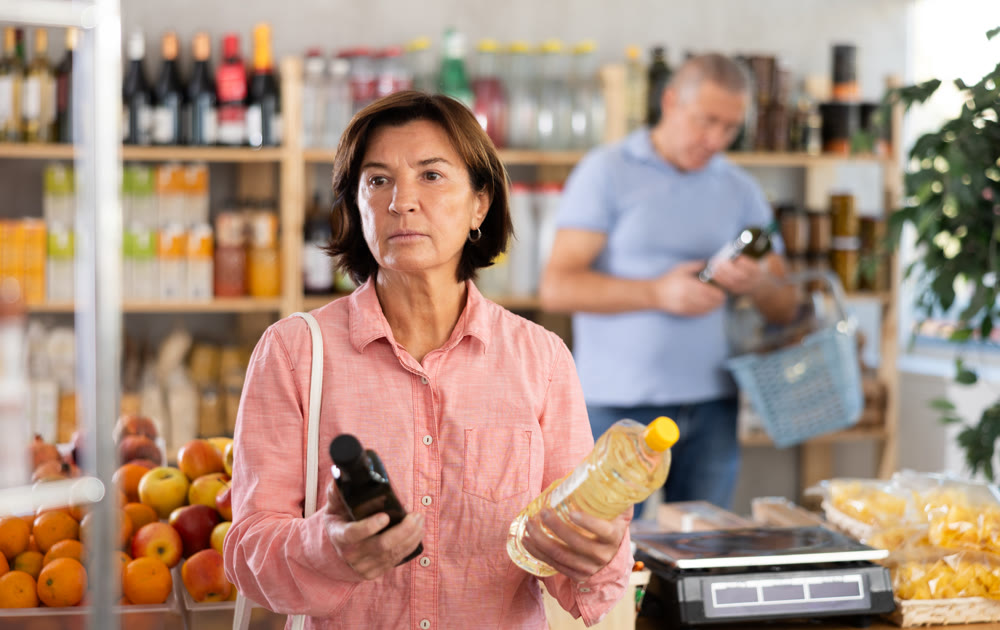 Elderly woman chooses vegetable oil in grocery store