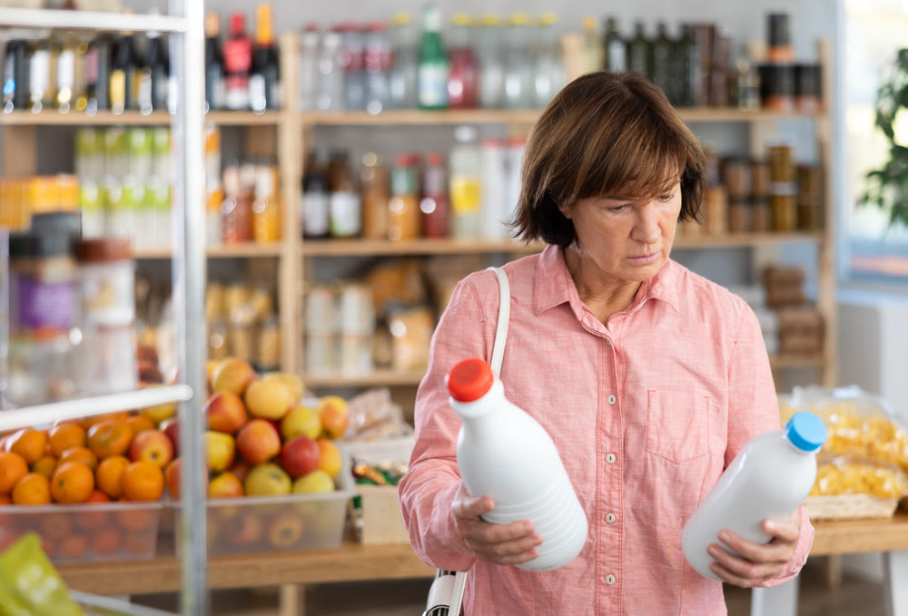 Mature woman choosing bottled milk in grocery store