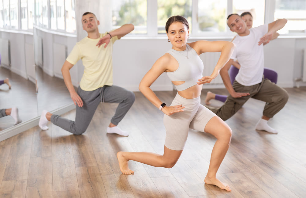 Young fit girl energizing group during dance fitness class