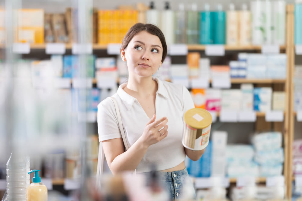 Young woman choosing baby formula in pharmacy