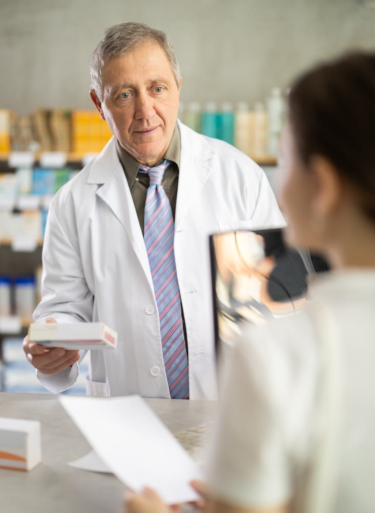 Senior man pharmacist consulting female client