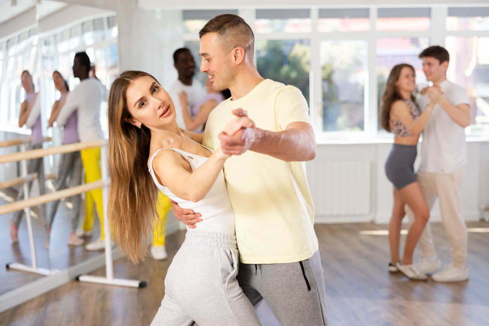Couple in sportswear rehearsing waltz at group dance class