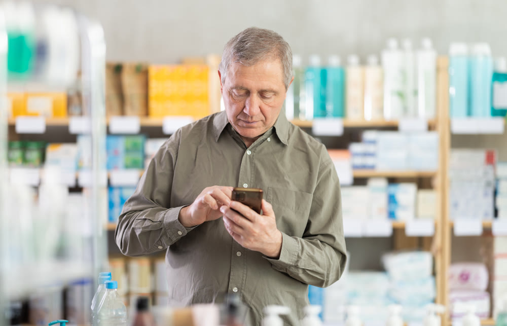 Senior man with phone is shopping in pharmacy