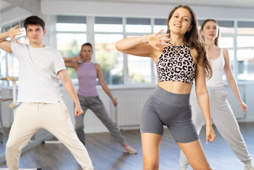 Group of men and women dance an energetic hip-hop dance in studio. Modern dance lesson