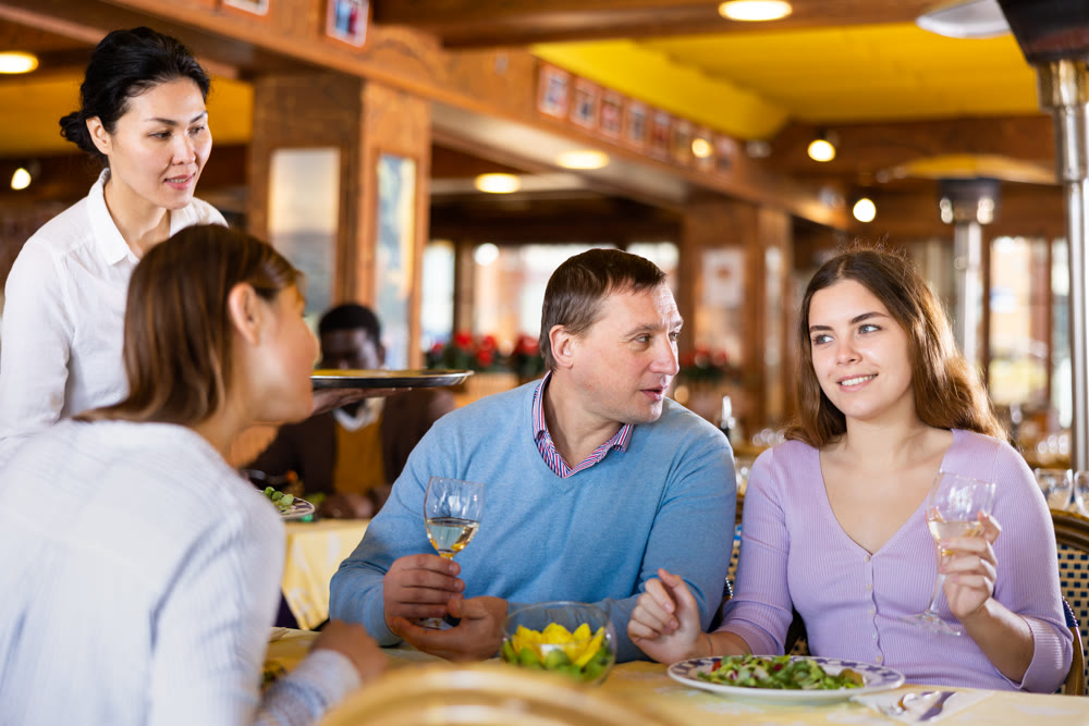 Man and two women eating and chatting in restaurant