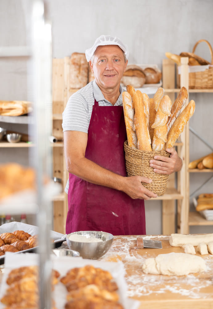 Elderly male seller showing assortment of bakery