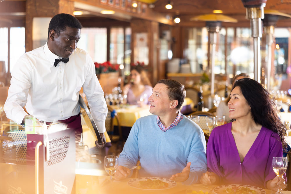 Man and woman talking with waiter in restaurant