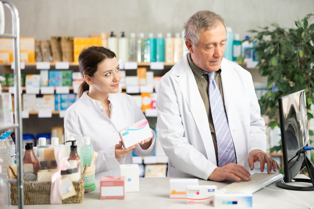 Male and female pharmacists looking for pills on computer