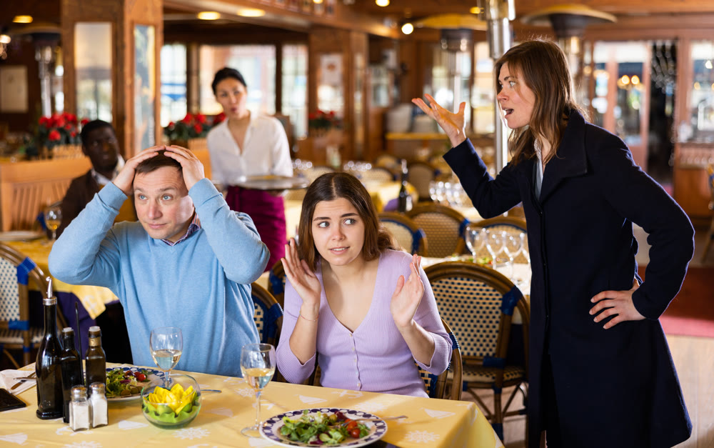 Wife scolding husband spending time with another woman in restaurant