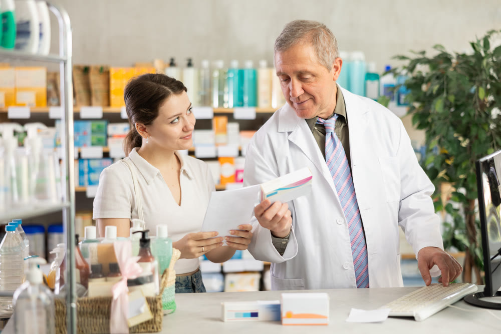 Senior man pharmacist use computer, girl intern with prescription