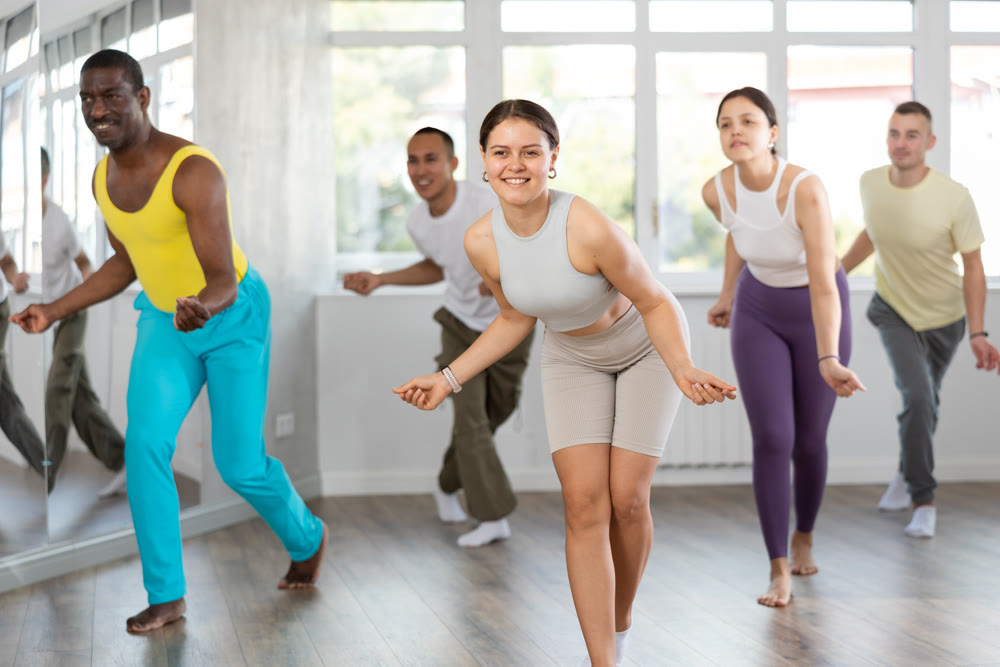 Young fit girl energizing group during dance fitness class