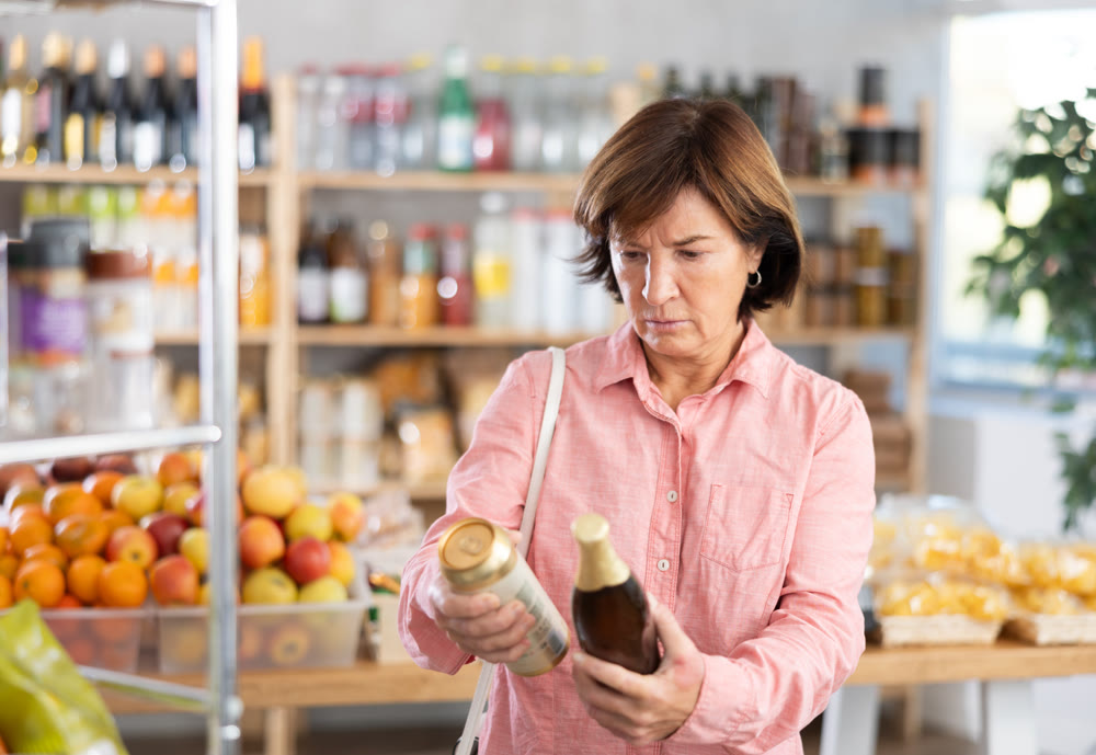 Choose alcohol in supermarket - woman chooses what beer to buy in alcohol section of store
