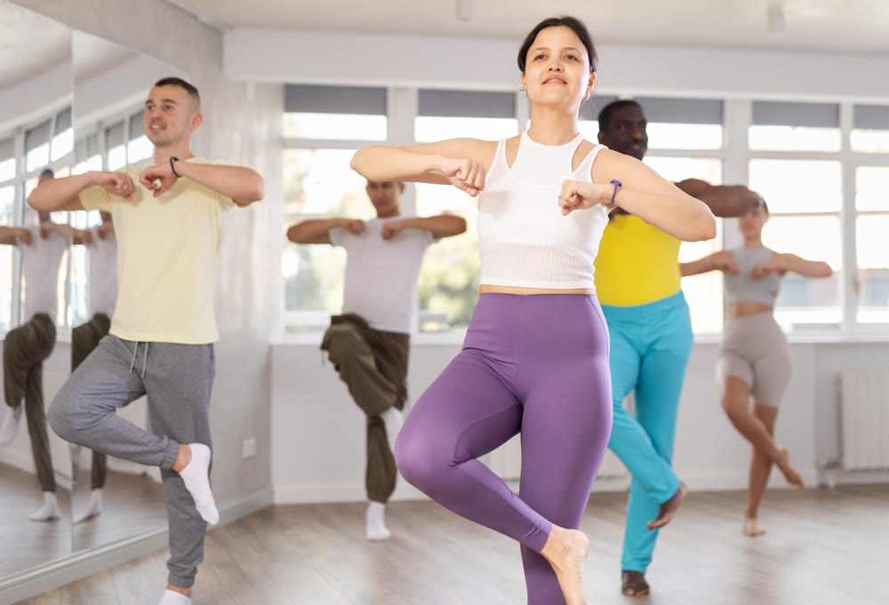 Young Asian woman practicing energetic dance at group class