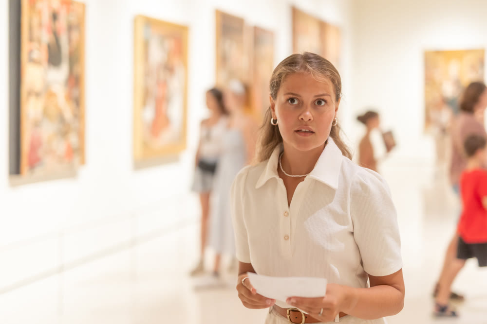 Portrait of young attractive woman holding an information booklet during a visit to fine arts museum