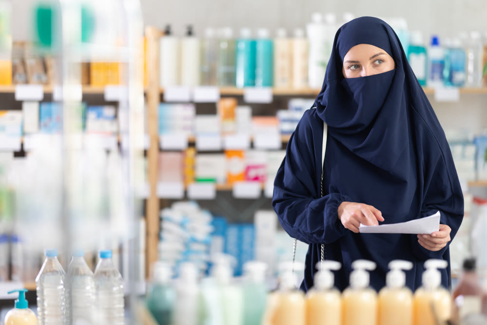 Muslim woman with prescription looking for medications in pharmacy