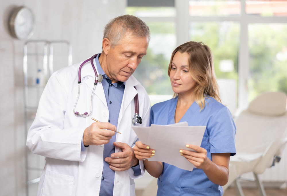 Experienced doctor advising female colleague about diagnosis of patient
