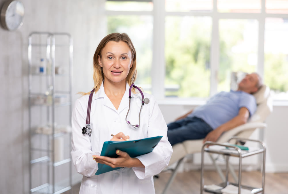 Positive female doctor standing in medical office with document folder