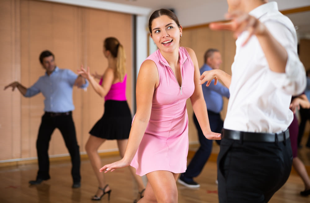 Cheerful female dancer practicing ballroom dances in ballroom