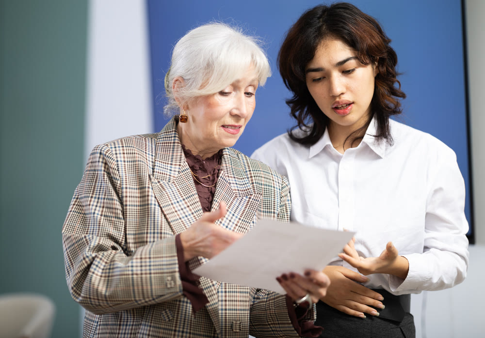 Young and elderly woman discussing document in office