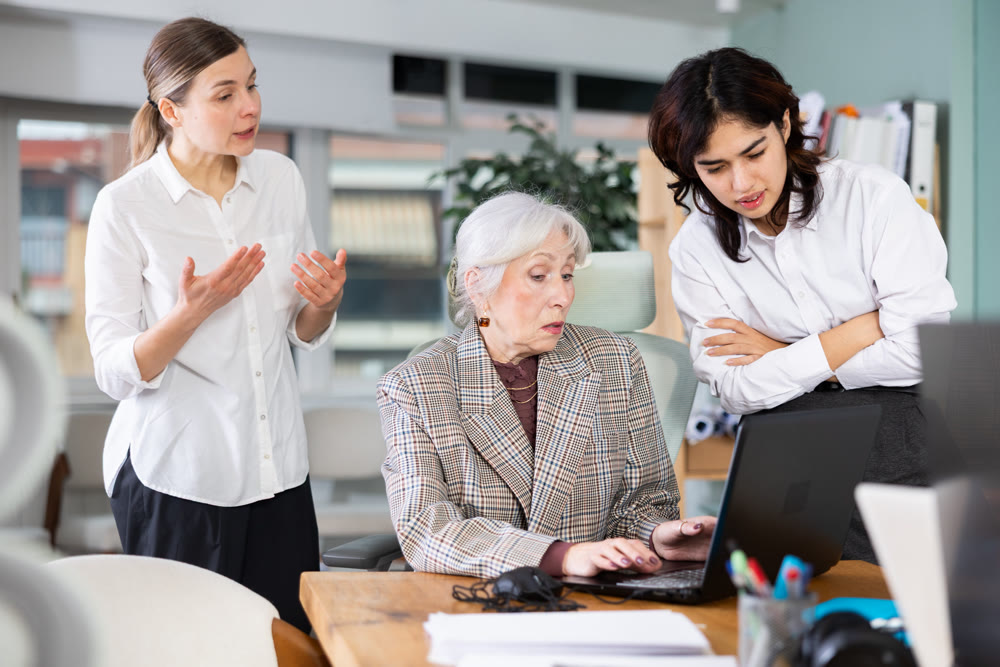 Group of women scolding sad colleague sitting at laptop in office