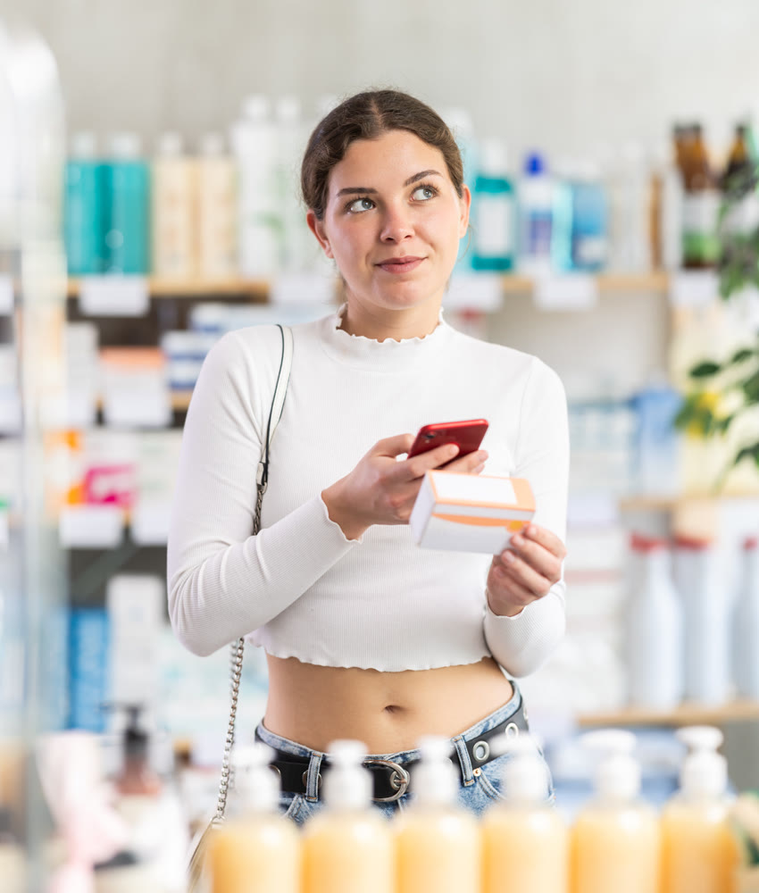 woman scans a package of pills with a mobile barcode in front of a counter in a pharmacy
