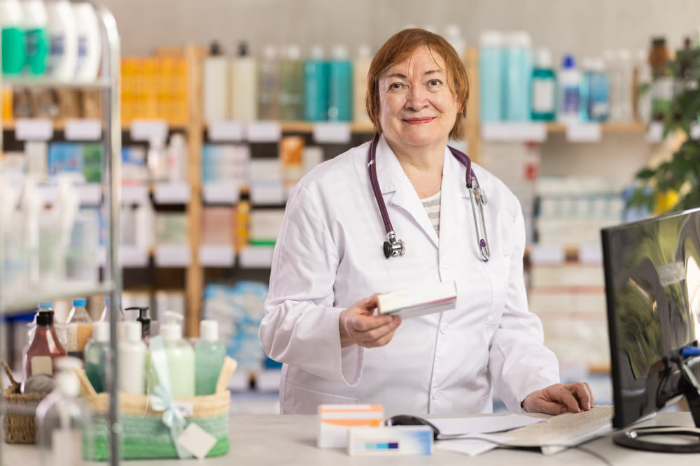 Professional elderly female pharmacist searches for information about medicines on Internet