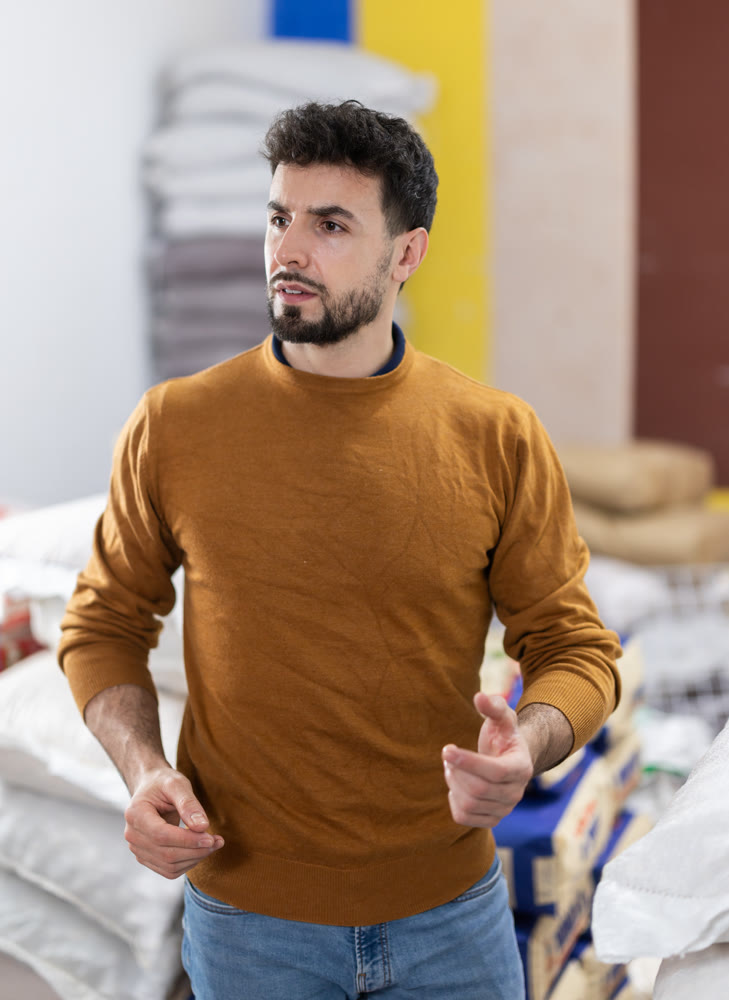 Male worker searches for something in supermarket warehouse