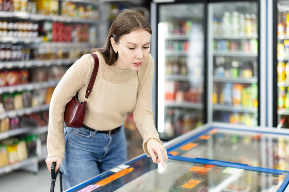 Young woman choosing frozen food in grocery store
