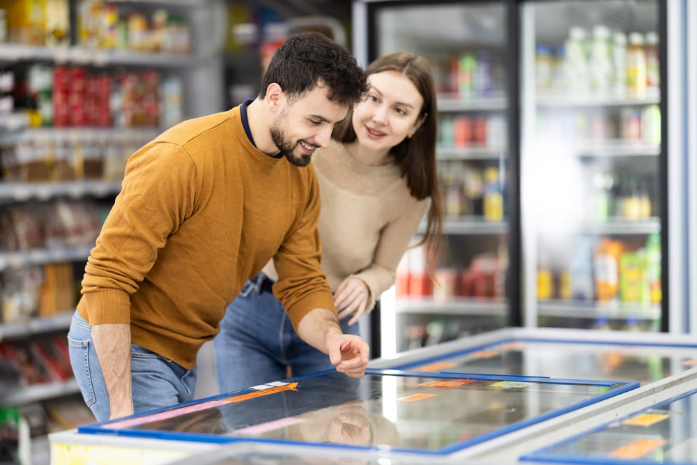 Couple spends time in store, looking for necessary goods and get out from refrigerator
