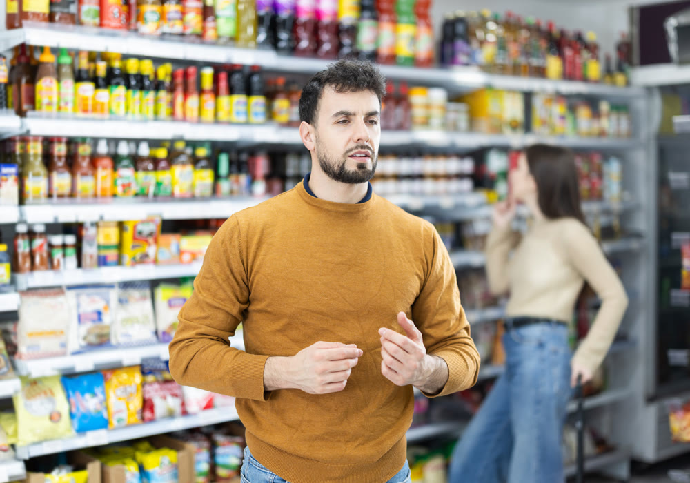 In food store, man buyer looking for something on shelf of showcase