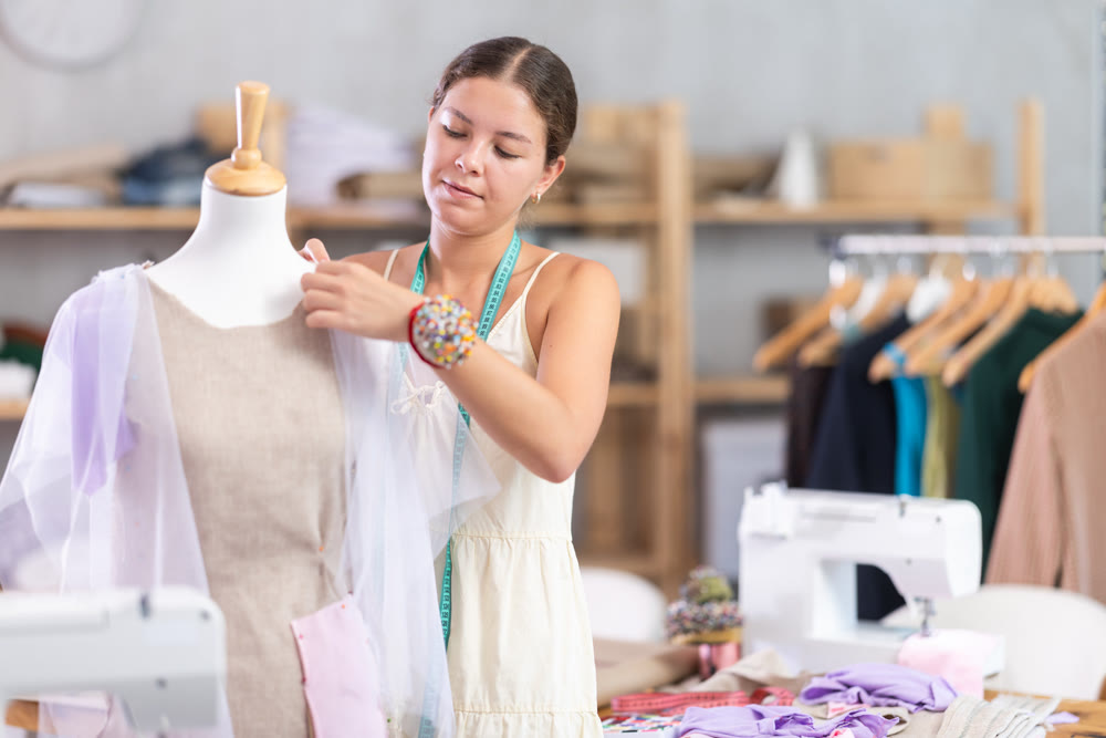 Girl designer works with mannequin and dress billet