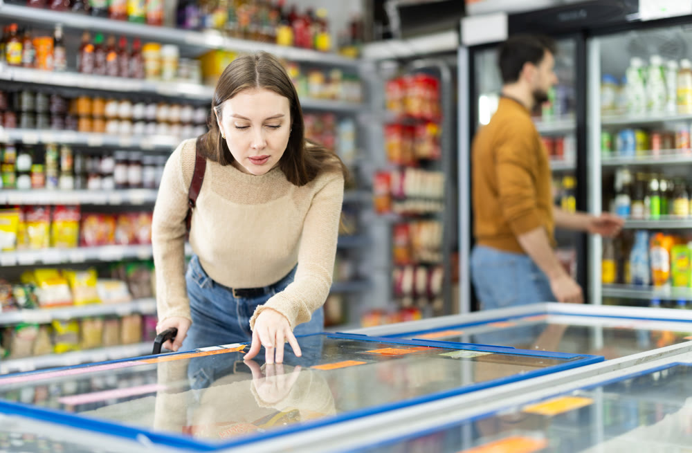 Young woman choosing frozen food in grocery store