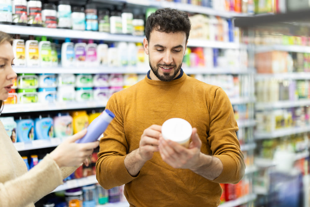 Young couple choosing body and hair care products in supermarket