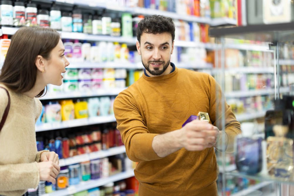 Couple choosing bottle of perfume in perfume shop