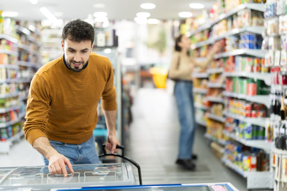 Man spends time in store, looking for necessary goods and get out from refrigerator