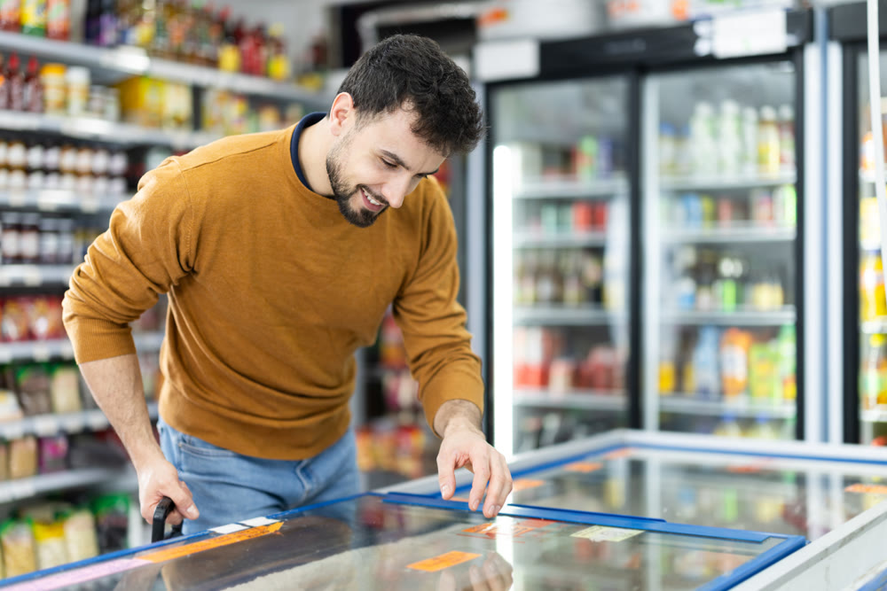 Man spends time in store, looking for necessary goods and get out from refrigerator