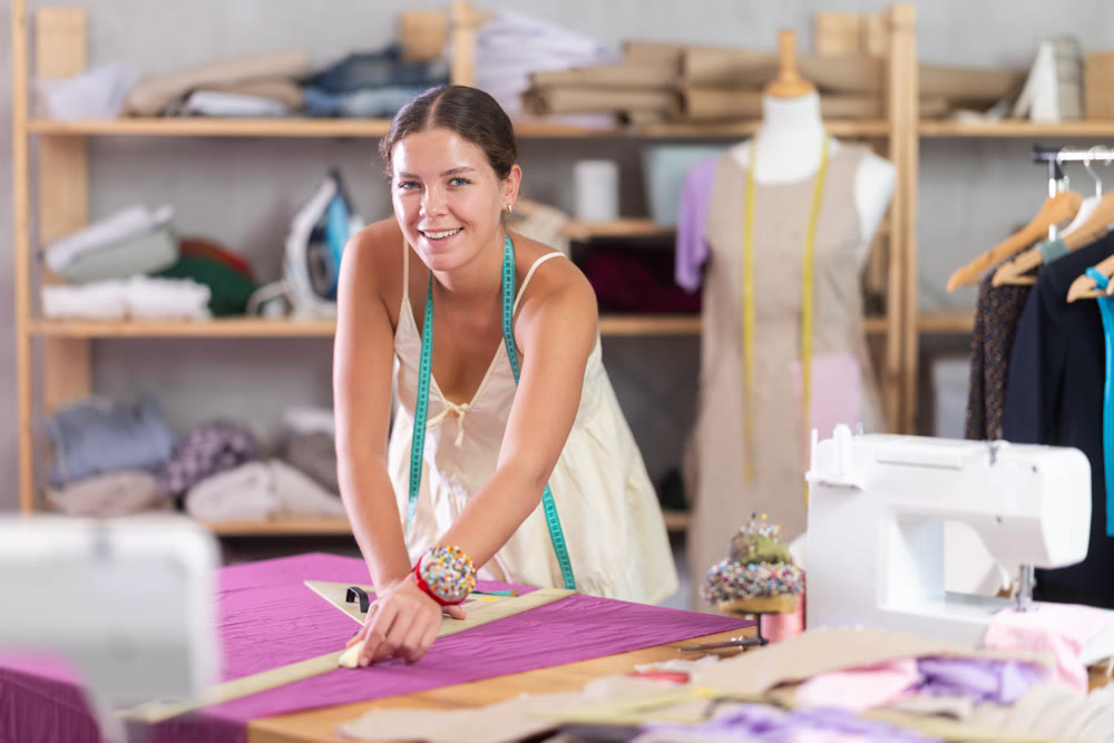 Using ruler, woman tailor draws dress diagram scheme on fabric