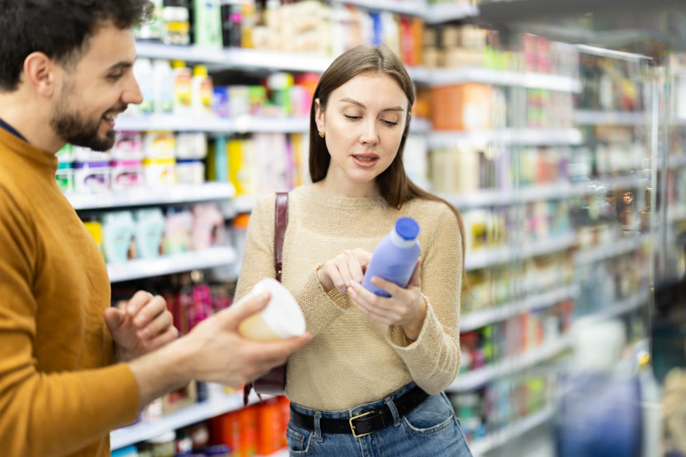 Married couple buyers chooses shampoo or shower gel in household chemicals store