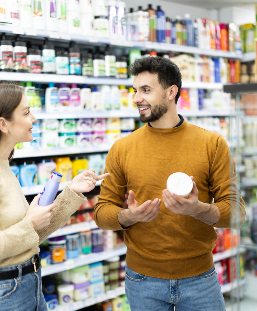 Married couple buyers chooses shampoo or shower gel in household chemicals store