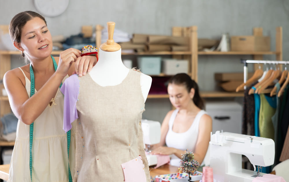 Tailor work with mannequin. Assistant sewing in background