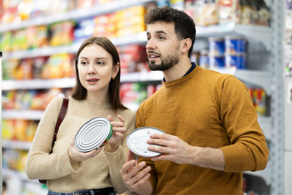 Couple in supermarket search and select product tin can