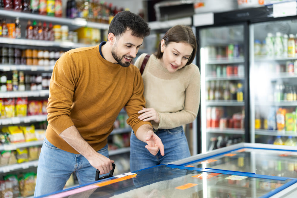 Young couple choosing frozen food in grocery store