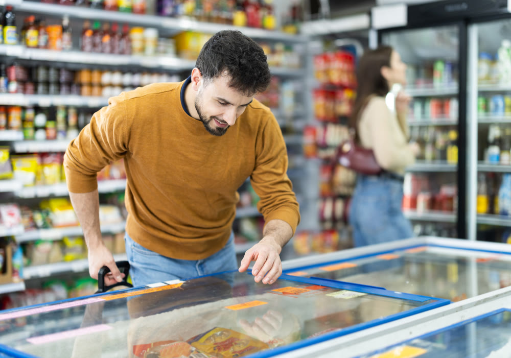 Man spends time in store, looking for necessary goods and get out from refrigerator