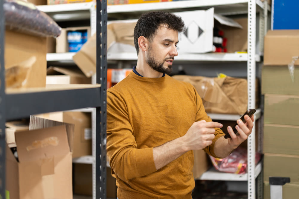 Young man scanning boxes in grocery warehouse