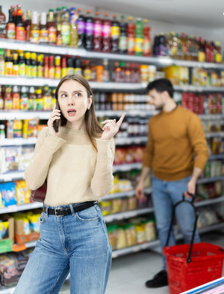 Female shopper talks on mobile phone while shopping at grocery store
