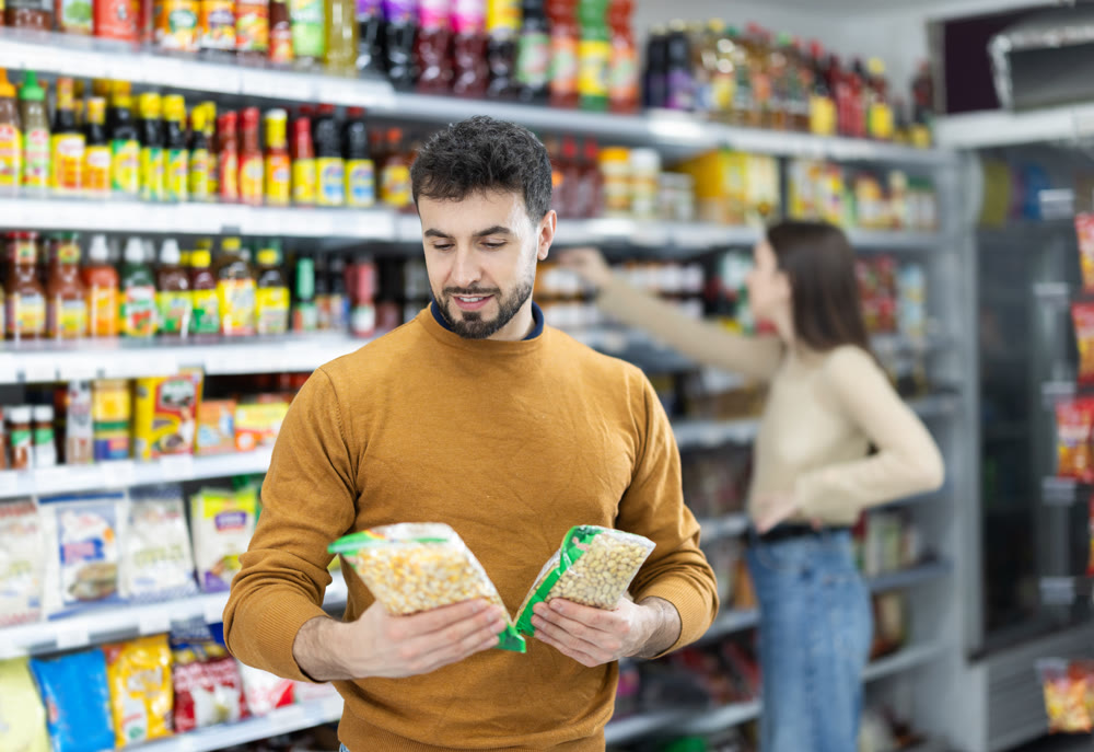 Man customer in supermarket search and select product beans