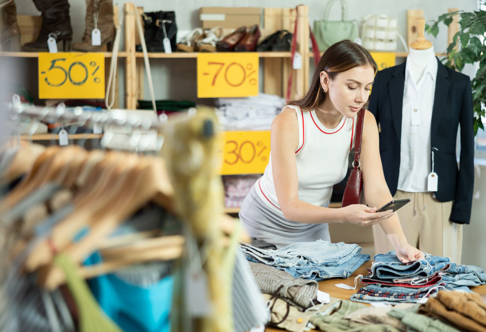 Young woman scanning pants tag during seasonal sale