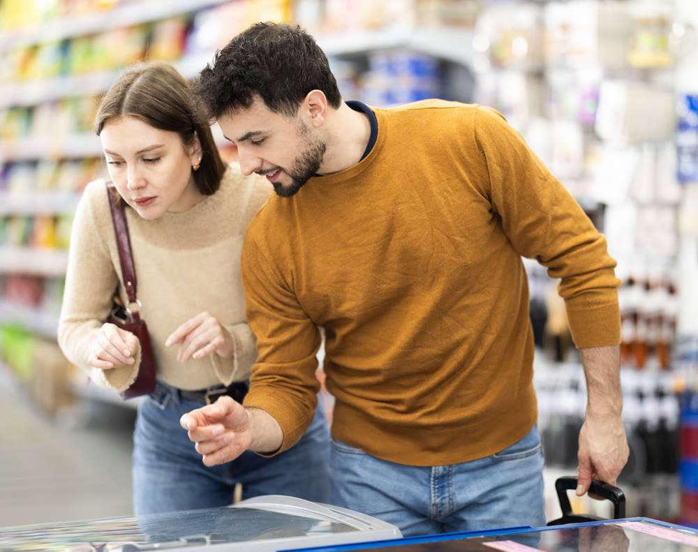 Young couple choosing frozen food in grocery store
