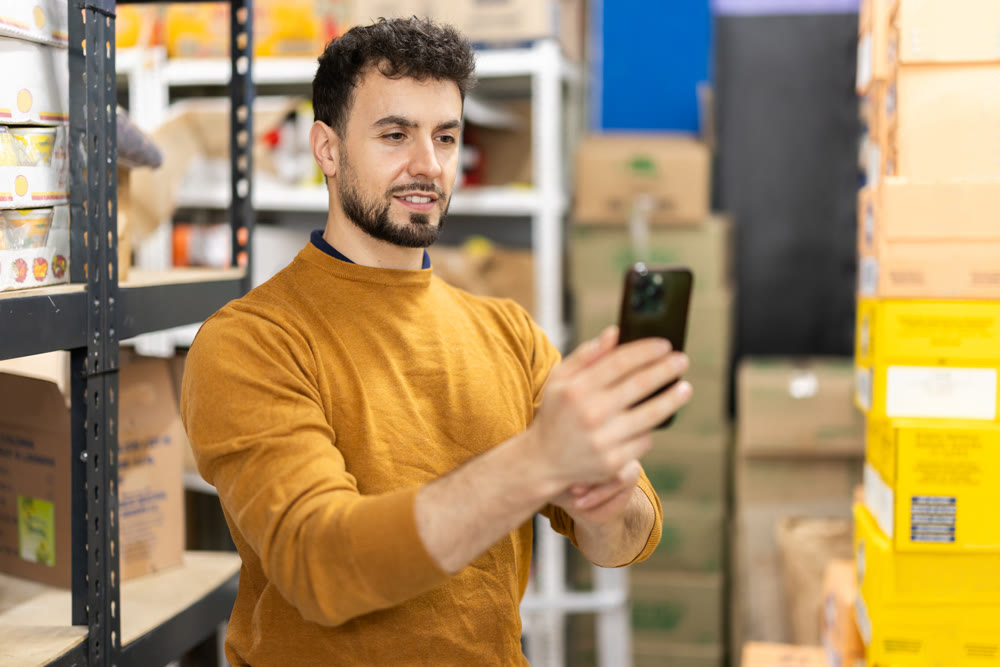 Young man scanning boxes in grocery warehouse